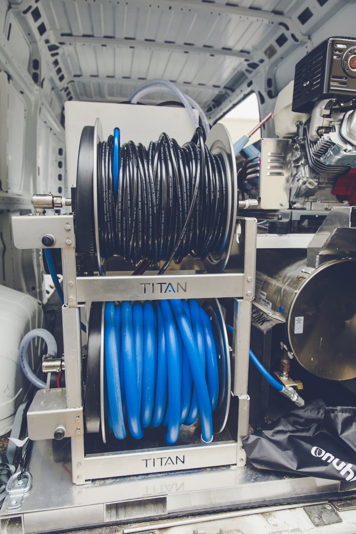 The stacked Titan dual hose reel in the van, both reels loaded: black hose on top, blue below.