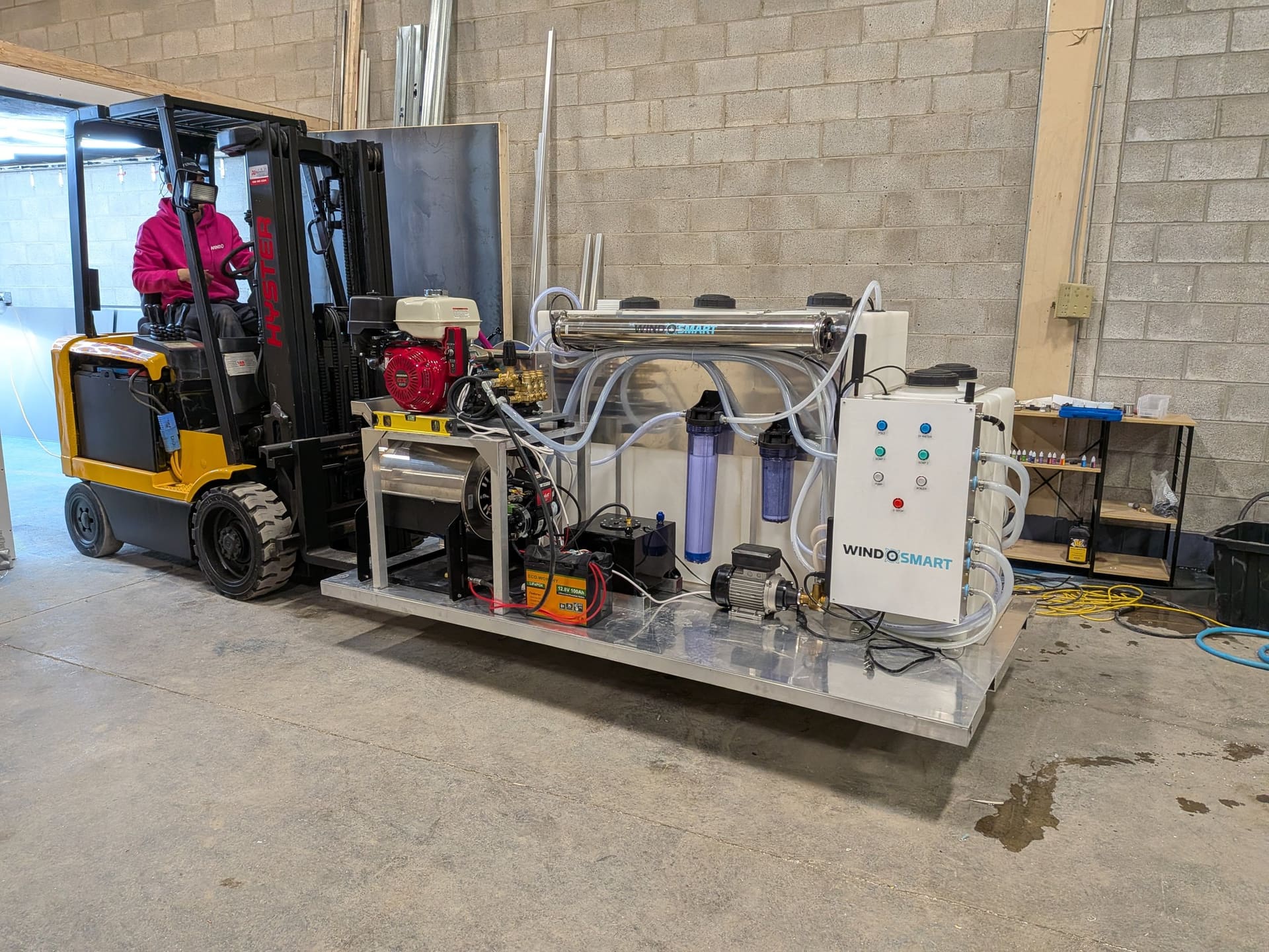 A WINDOSMART skid on a forklift: the WINDOSMART-branded RO housing across the top, two clear filter housings, the white control box and an engine-driven pump.