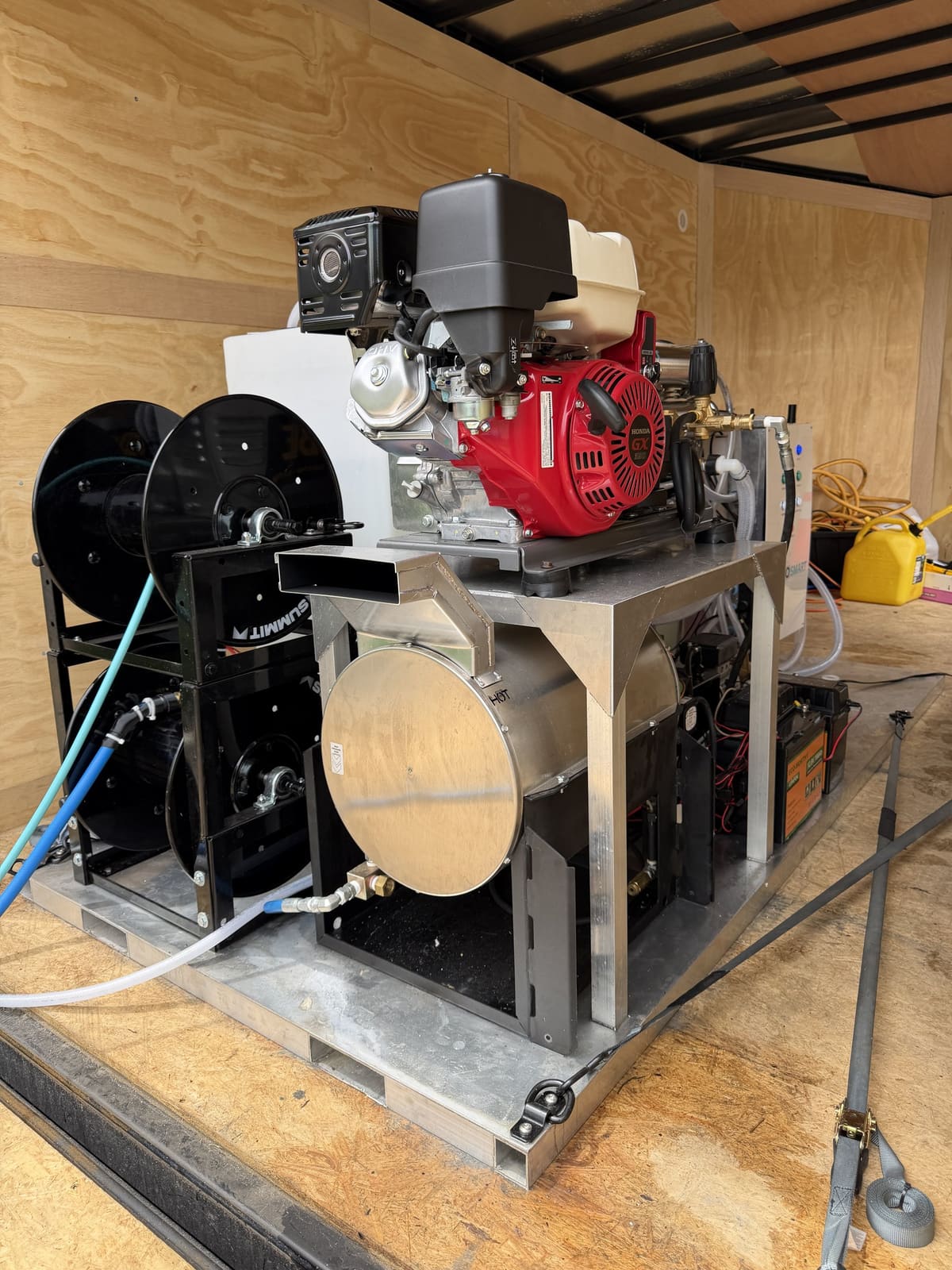 Inside the trailer: an engine-driven pump on the skid, two stacked hose reels and a round stainless unit.